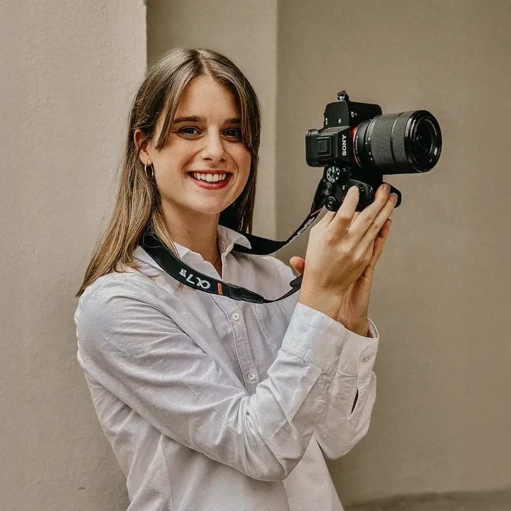 Ann-Kathrin Spöri mit einer Kamera in der Hand. SIe lächelt in die Kamera. - Social-Media-Agentur-B2B-#15