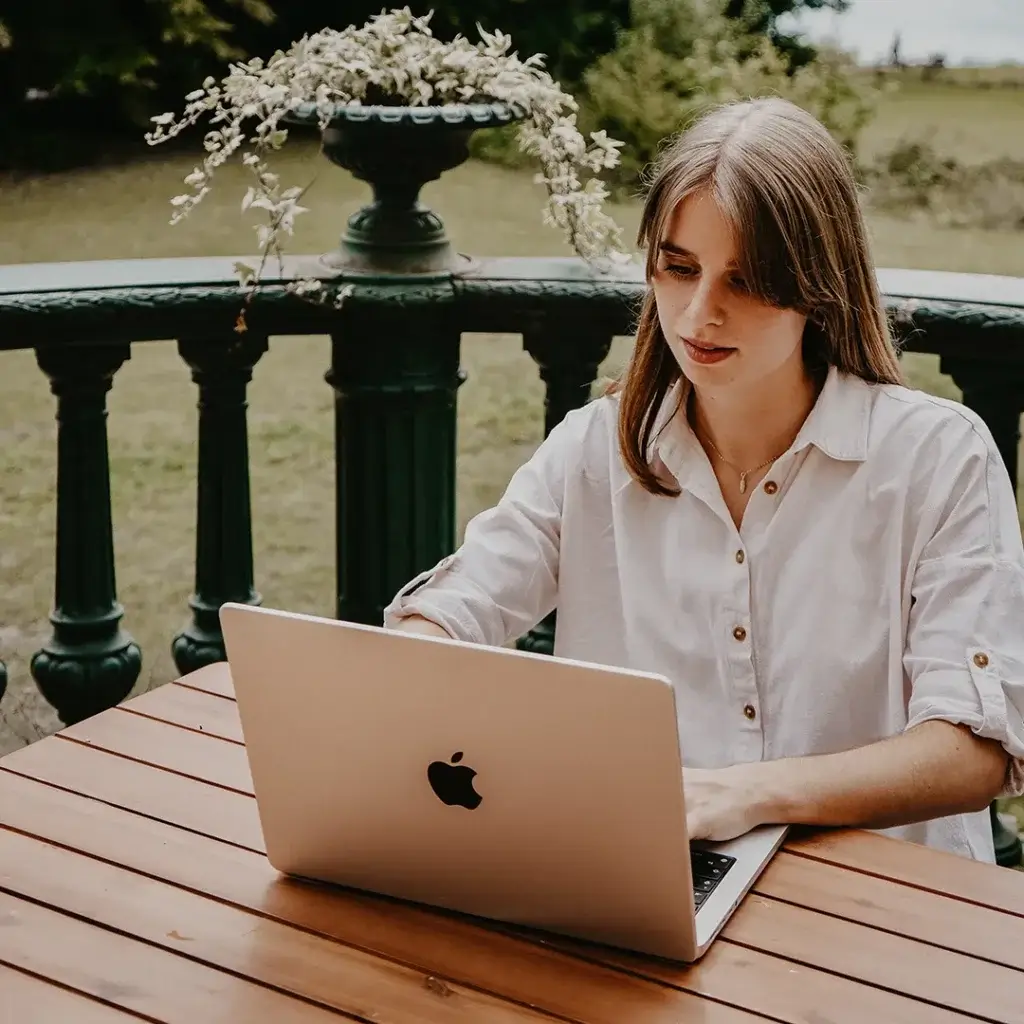 Ann-Kathrin Spöri arbeitet mit ihrem Laptop auf einer Terasse im Hintergrund ist ein See zu sehen - Social-Media-Agentur-B2B-#8